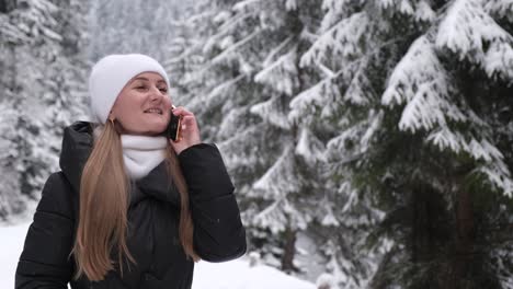 happy Girl Walks through a Snowy Forest and Talks on the Phone Young Girl Woman with Mobile Phone Walks in Beautiful Winter Forest among Trees Firs Covered with Snow