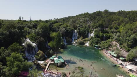 drone flyover crowded tourist area of kravica waterfall, scenic landscape in bosnia and herzegovina