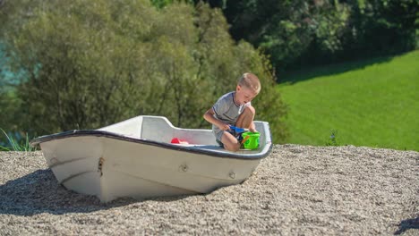 kid play in sandbox on playground, pours sands in bucket with shovel