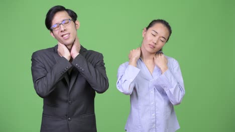 young asian business couple having neck pain together