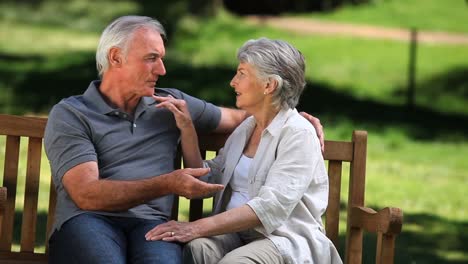 Senior-couple-laughing-on-a-bench