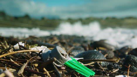 Stunning-shot-of-washed-up-plastic-on-a-beach,-before-a-wave-comes-and-surrounds-it-in-foamy-water