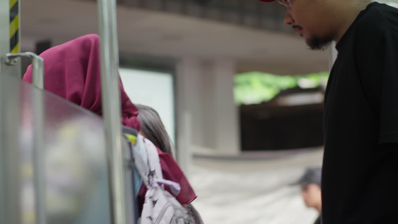 Man wearing a mask boards a train at Kampung Bandan station as it prepares to depart