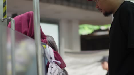 man wearing a mask boards a train at kampung bandan station as it prepares to depart