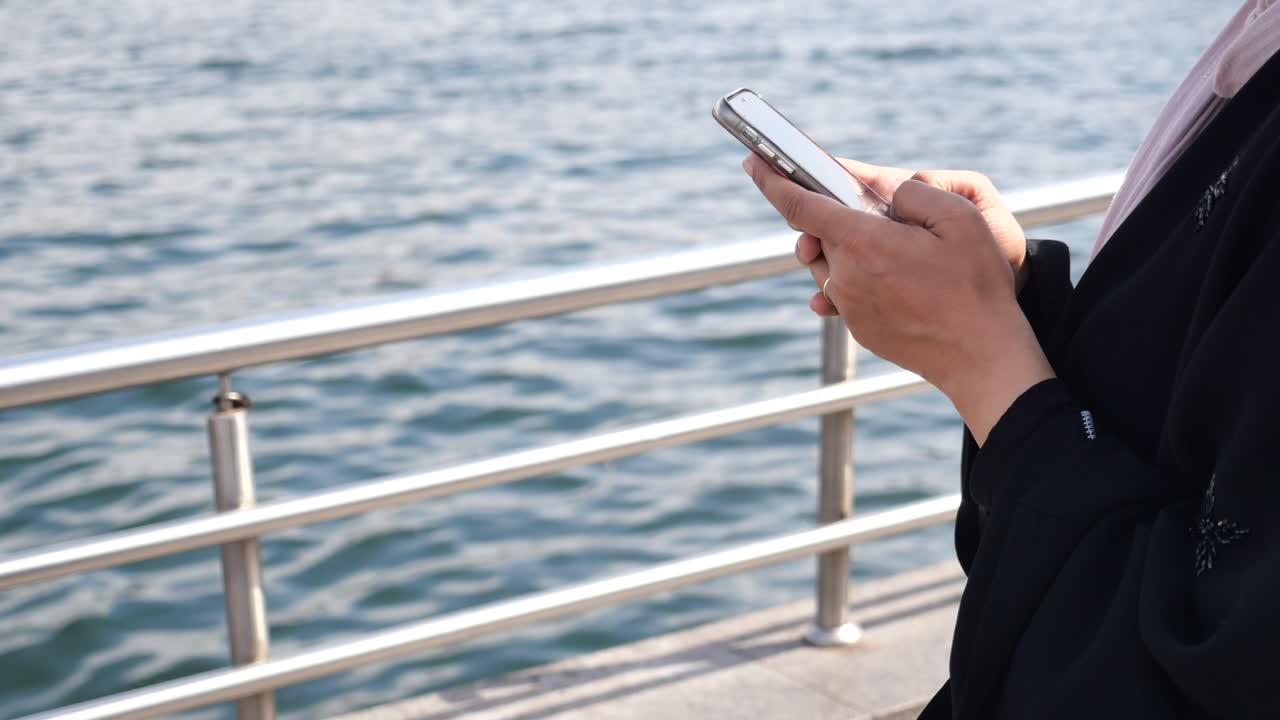 水辺でスマートフォンを使う女性
