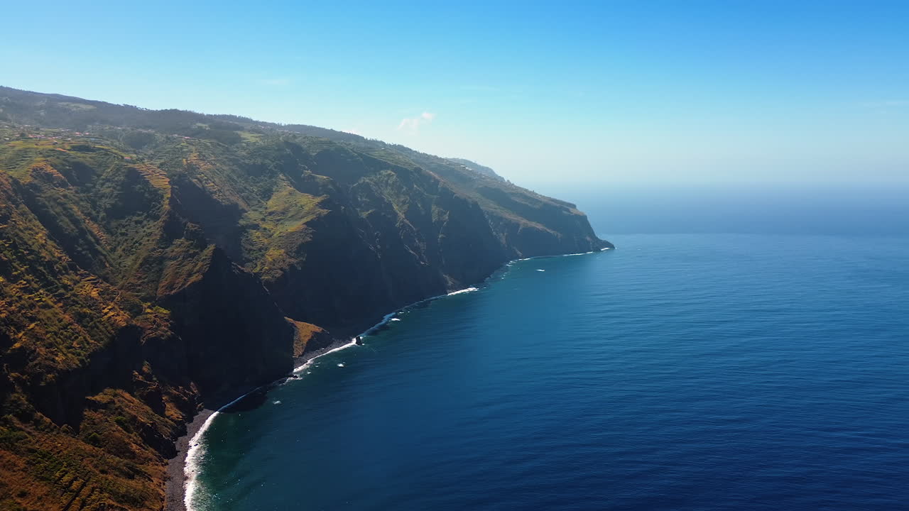 High rocky cliffs at the coast of the Atlantic Ocean. Drone footage above the peaceful waterscape on the shore of the Madeira Islands, Portugal.