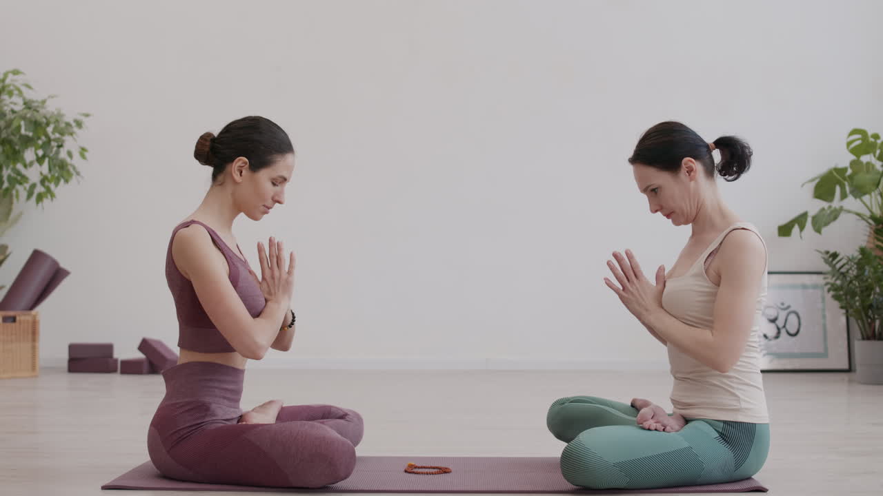 dos mujeres meditando en el estudio de yoga