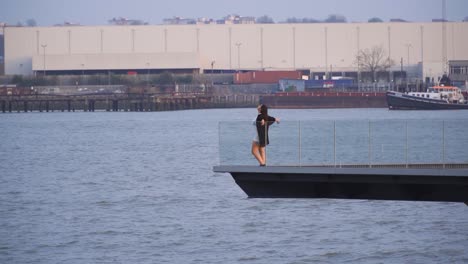 attractive woman in far away surrounded by water sea going to the edge of the platform to enjoying herself feeling free relaxing resting her hands on rail fence hair flying around boat docks waves