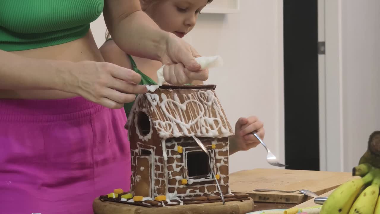 madre y hijo decorando una casa de pan de jengibre
