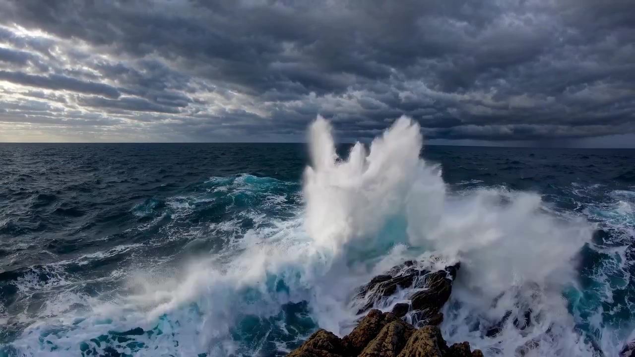 Kraftige havbølger som slår mot en steinete kystlinje under en stormfull himmel