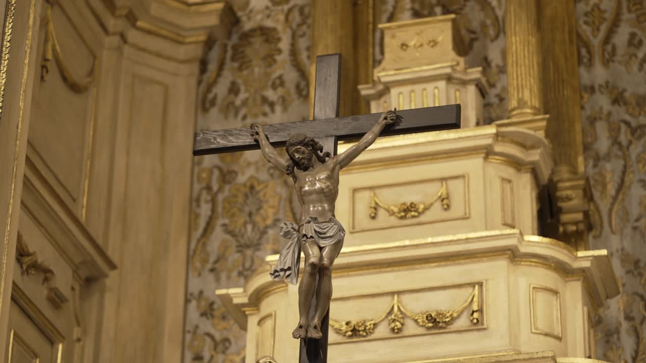 Statua del crocifisso di Gesù sulla croce, esposta in evidenza su un altare di chiesa ornato con intricati dettagli dorati