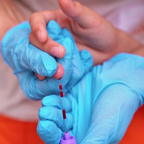 nurse in blue gloves collecting blood. close-up hands of a medical assistant taking blood sample from kid's finger.