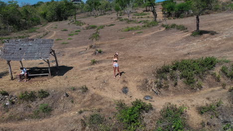 Junges-Weißes-Schönes-Frauenmodell,-Das-Auf-Klippe-Steht-Und-Im-Bali-Indonesien-Luxusklippenresort-Winkt