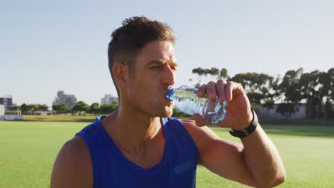 Hombre-Caucásico-En-Forma-Haciendo-Ejercicio-Al-Aire-Libre,-Descansando,-Bebiendo-Agua