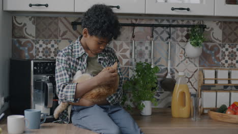 boy holding a ginger cat in the kitchen