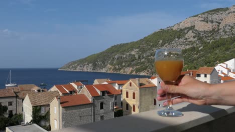 mujer bebiendo jugo en el balcón con vistas al mar, la montaña y la ciudad, croacia