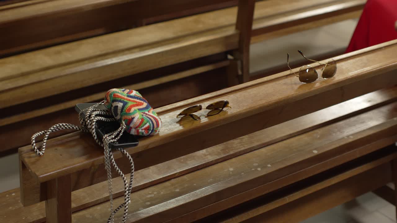 Sunglasses and colorful accessories placed on wooden benches in an indoor setting