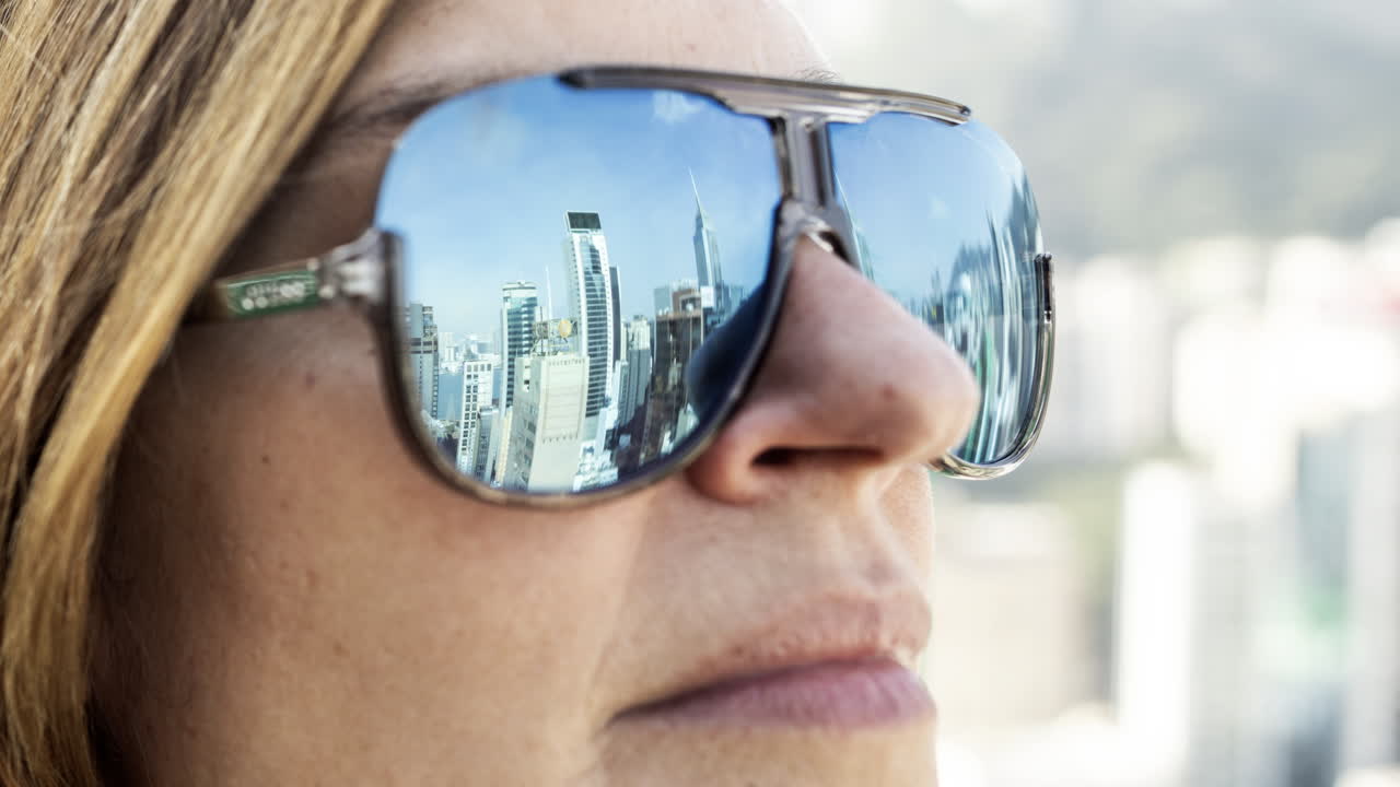 Close Up of Woman's Face with City Skyline Reflected in Sunglasses