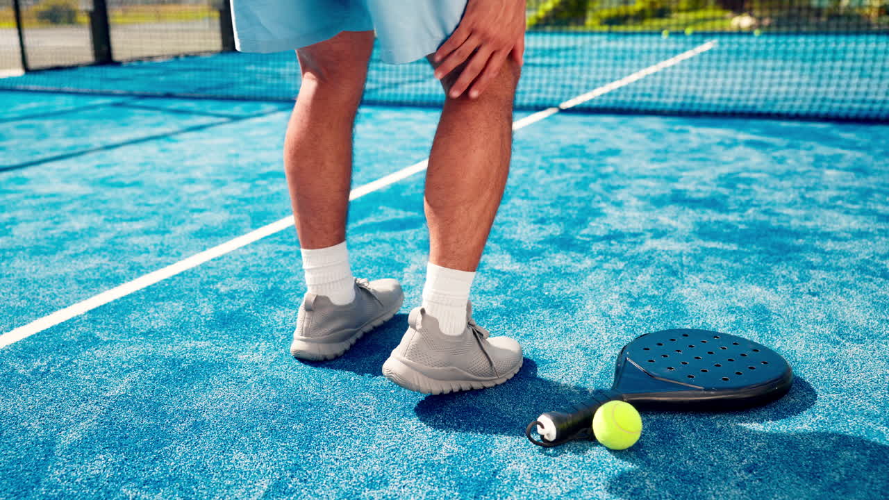 Uomo che prova dolore alla gamba su un campo da padel