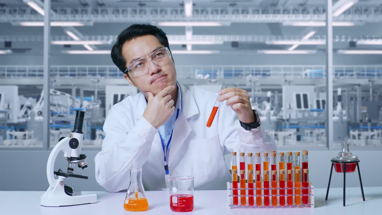 아시아 남성 과학자가 시험관에서 생각하고, 주위를 둘러보며, 지표손가락을 들고, 현미경과 함께 실험실에서 실험실에서 플을 분석합니다.