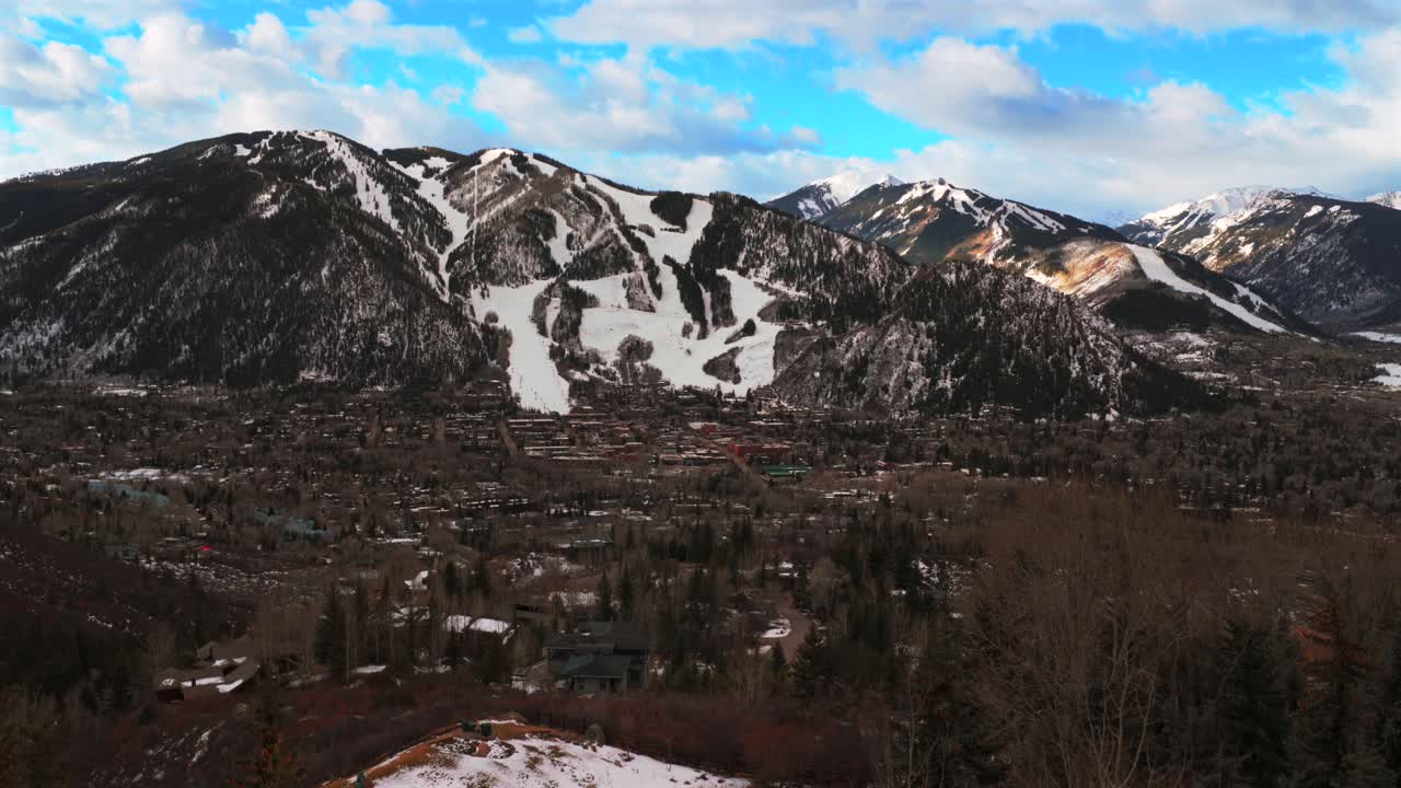 Mattina nuvolosa, ripresa aerea con drone del centro della cittadina sciistica di AJAX Mountain nella Aspen Valley in inverno, Colorado. Si vedono il resort sciistico Aspen Highlands, piste da sci nella Maroon Bells Wilderness, seggiovie, cabinovie e edifici residenziali, con una panoramica in avanti verso l'alto.