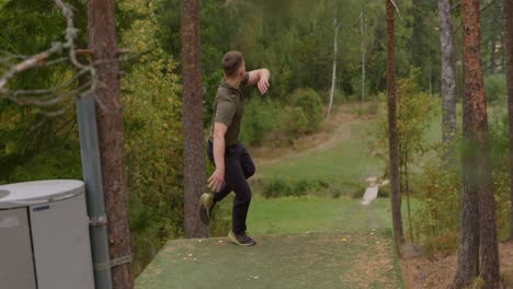 disc golfer throwing a backhand throw from a higher up tee - full shot