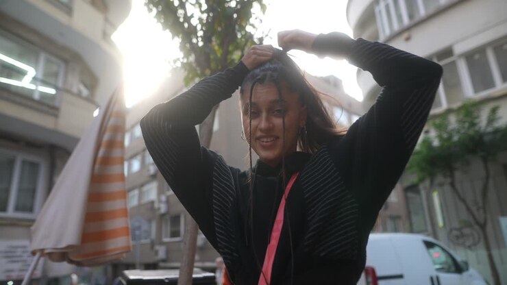 Young woman styling her hair outdoors
