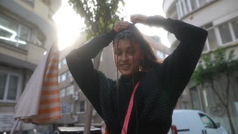 una mujer joven estilizando su cabello al aire libre.