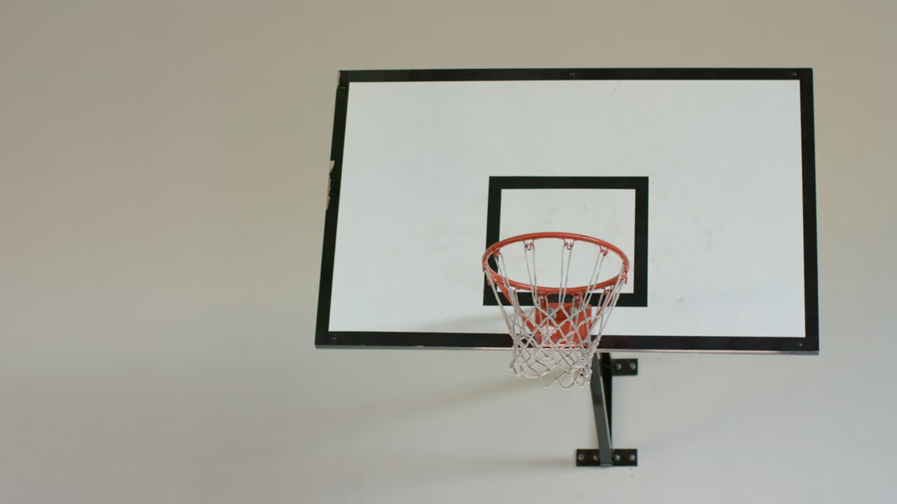 Playing basketball, woman shooting ball towards hoop in indoor court, copy space