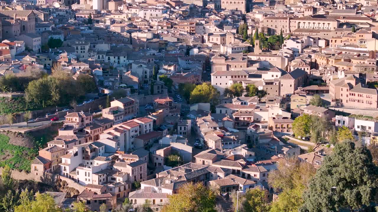 Ascending drone shot moving forward through Toledo’s narrow medieval streets toward the majestic Gothic Cathedral, revealing the charm of its old town and the horizon under a bright autumn sky