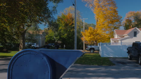 a child sends a letter - throws it into a blue mailbox on a typical american street