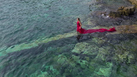 una turista con un vestido rojo nada en el mar adriático en croacia.