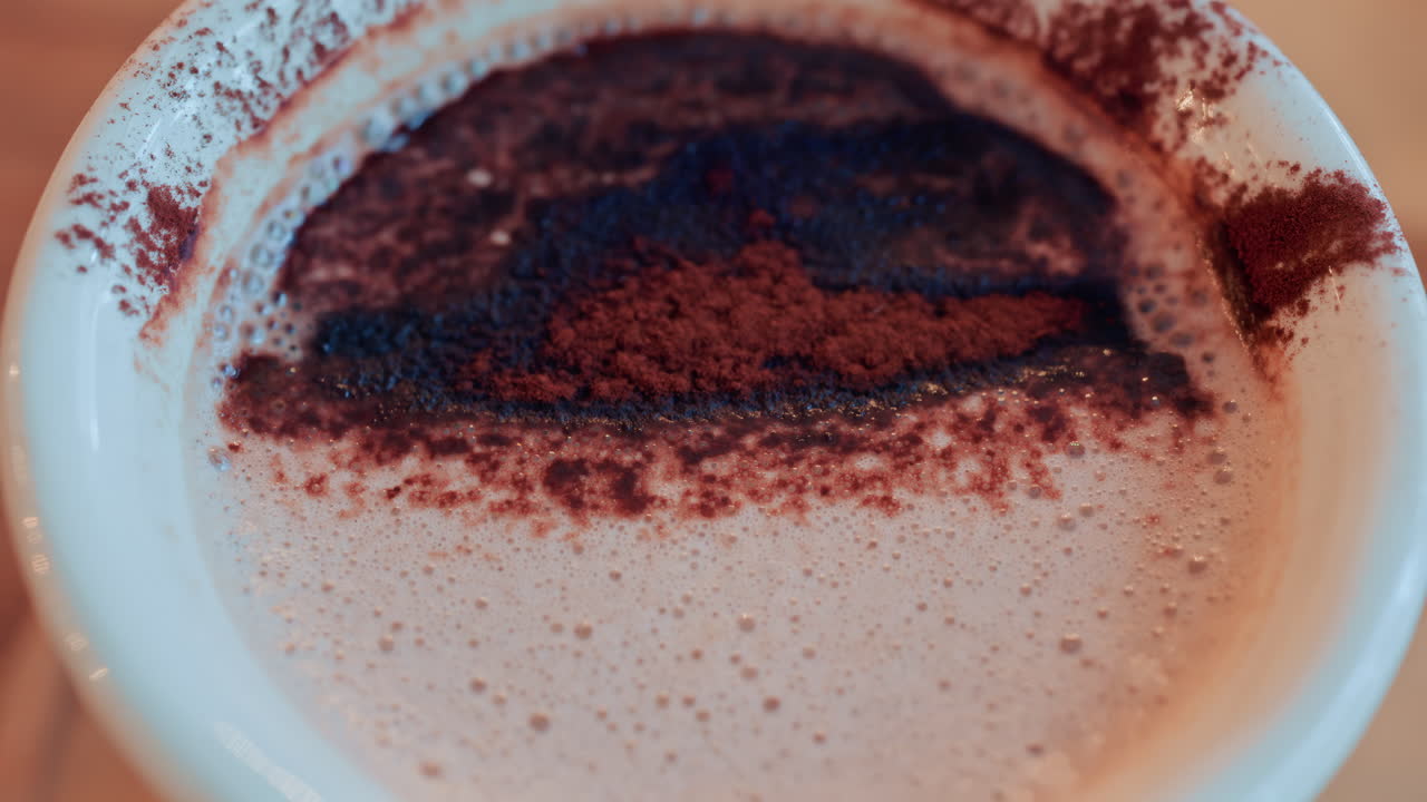 Primo piano di una ricca superficie di cioccolata calda o caffè cosparsa di cacao in polvere
