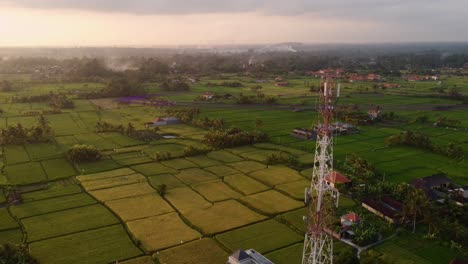 Aerial-5G-6g-tower-in-rural-countryside-during-sunset,-micro-waves-pollution-animation-smart-city-fast-internet-data-for-global-connection
