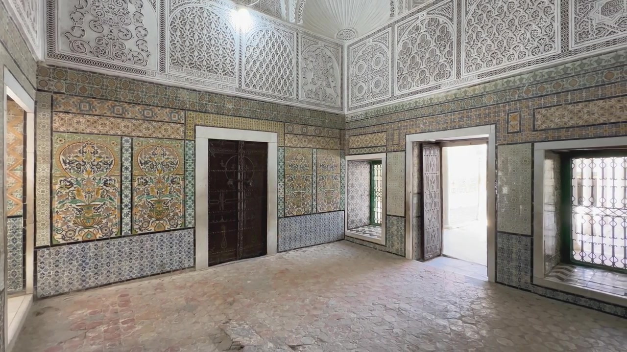 Interior histórico con detallados azulejos islámicos, arcos de yeso tallados y cúpula iluminada por candelabros en la Zawiya de Sidi Sahib, también conocida como la Mezquita del Barbero en Kairouan. Túnez