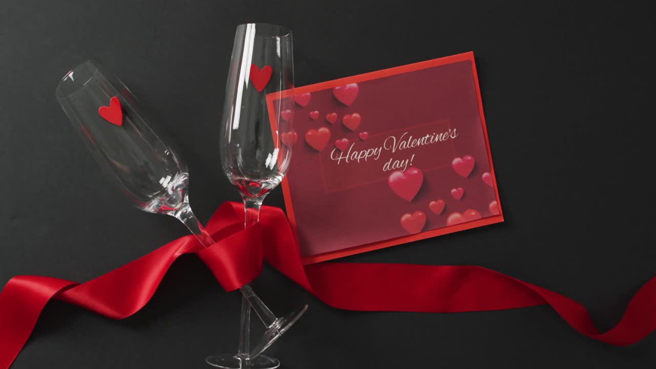 Happy valentine's day text over champagne glasses with hearts and red ribbon