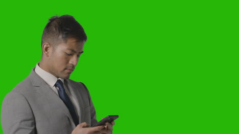 retrato de hombre de negocios en traje contra mensajes de pantalla verde en el teléfono móvil