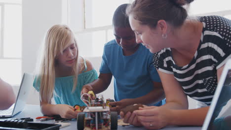 Zwei-Schüler-Mit-Einer-Lehrerin-Im-Computerprogrammierungskurs-Nach-Der-Schule-Lernen,-Roboterfahrzeuge-Zu-Programmieren