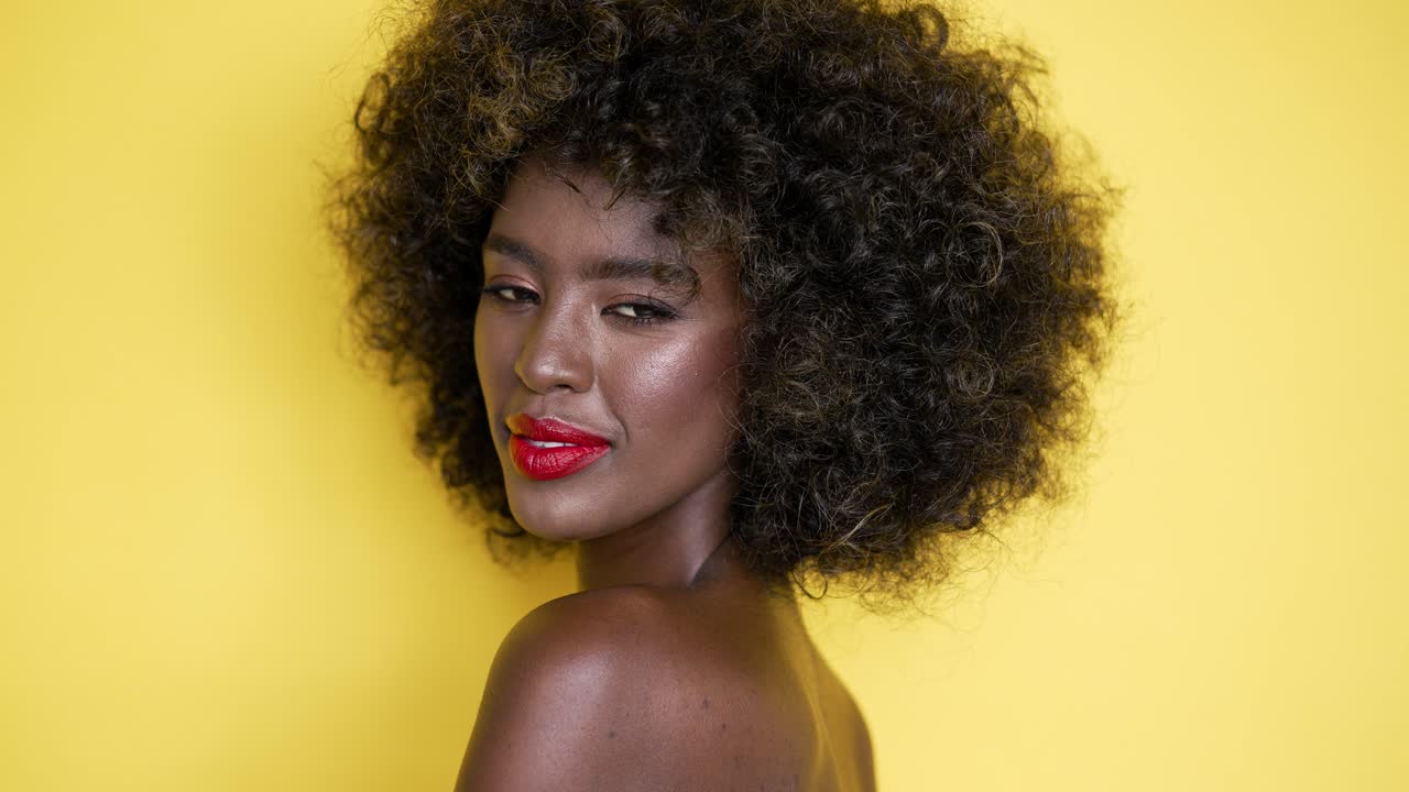 mujer con cabello afro y labios rojos en fondo amarillo