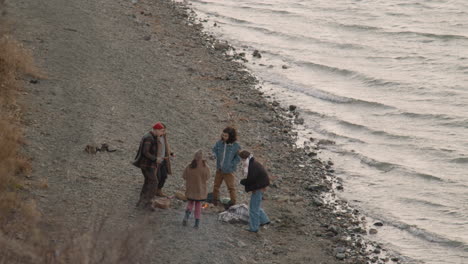 海岸でお茶を飲み、ソーセージを食べながら、たき火の周りの10代の友人のグループの恐怖の眺め