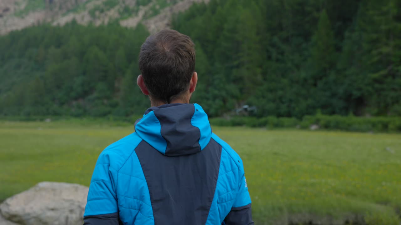 사람 의 머리 와 어깨 의 뒷면 을 보면서 드론 이 산 들 의 초원 에서 야외 에서 날아가는 것 을 보고 있다