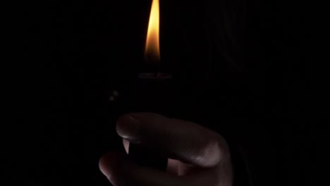 hands around a candle at vigil close up shot on dark background
