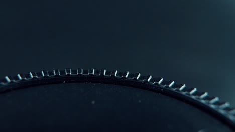 a macro close up professional shot of a black plastic wheel on a 360 rotating stand, cinematic studio lighting, 120 fps, slow motion, full hd video