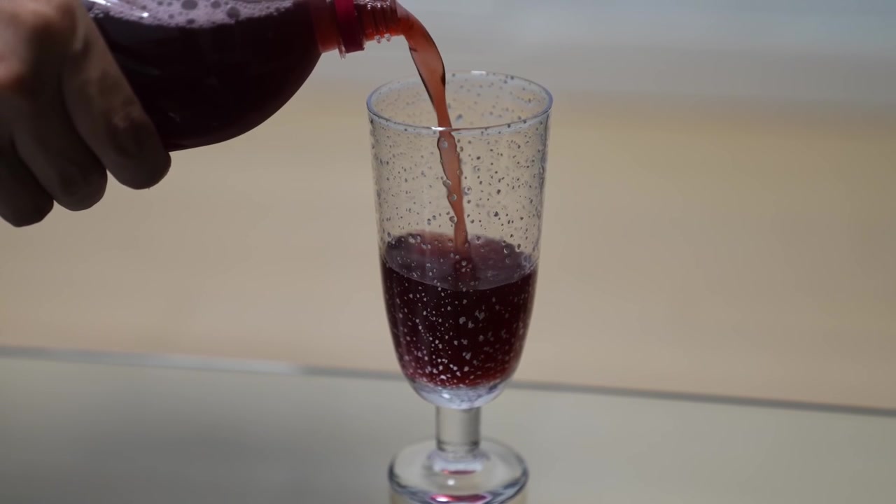 Il vino rosso viene versato in un bicchiere a stelo artigianale per dimostrare la qualità del prodotto finito