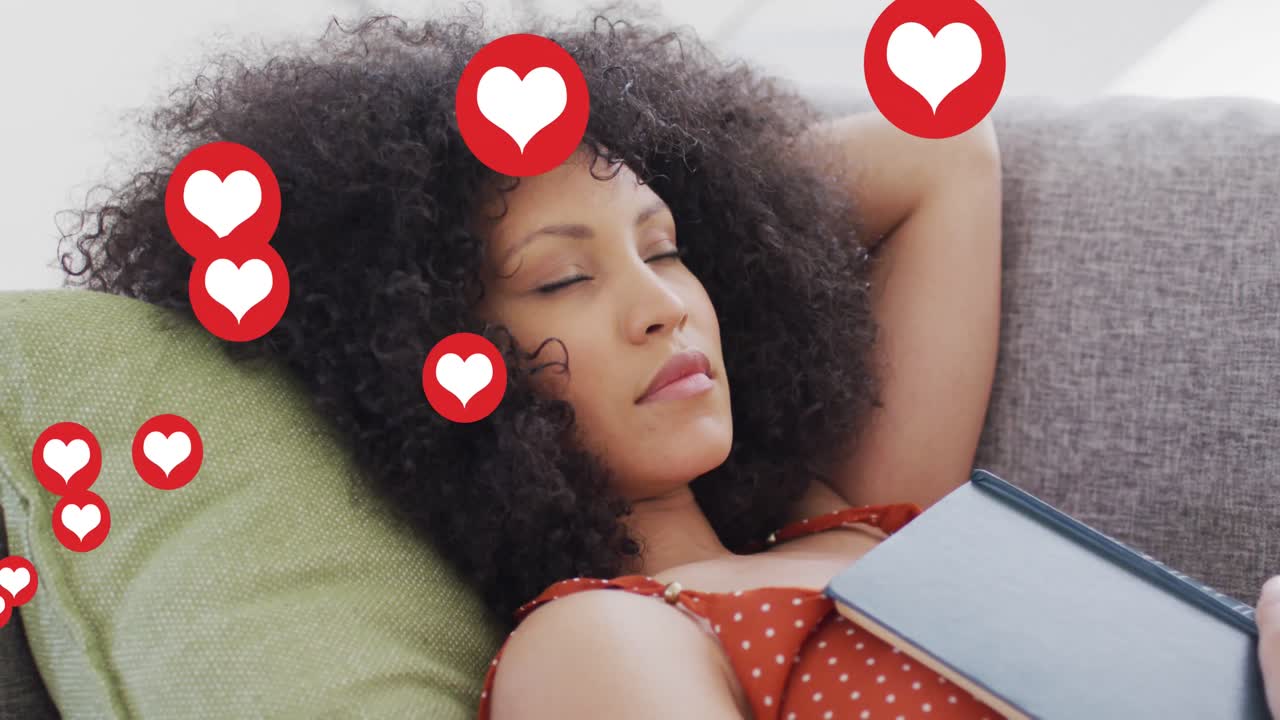 animación de los iconos del corazón de las redes sociales sobre una mujer biracial durmiendo en el sofá