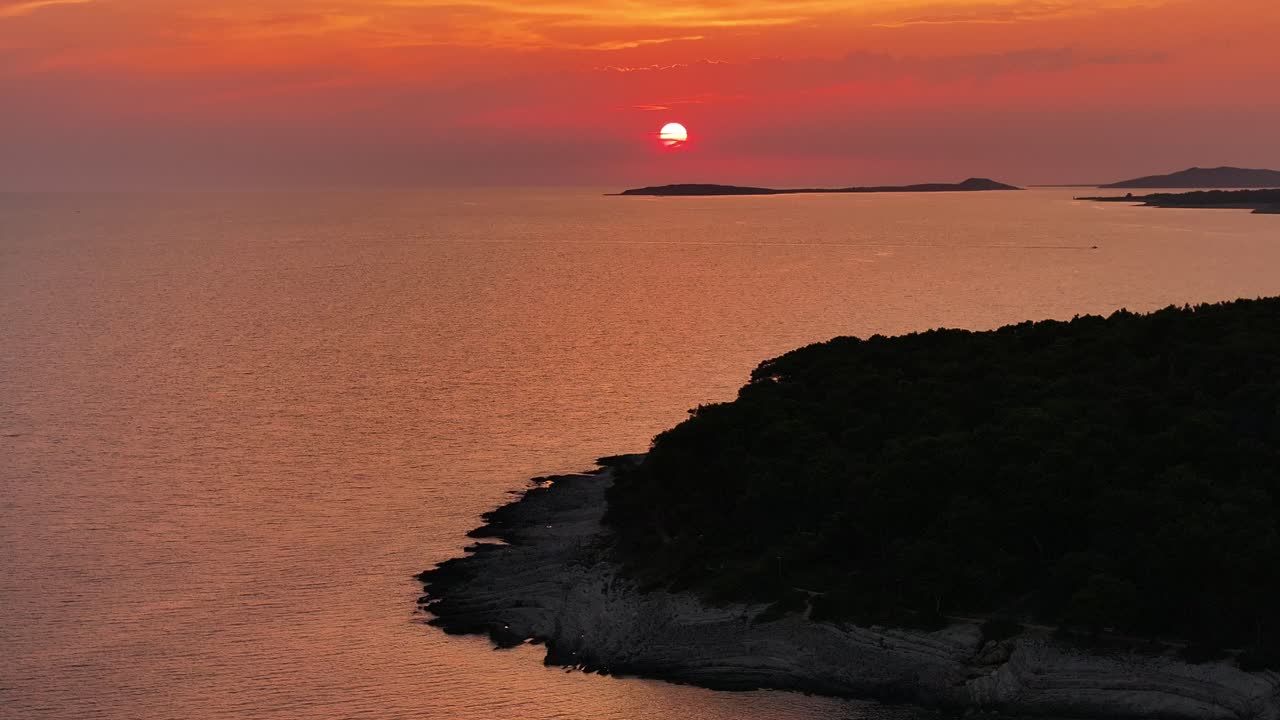 Capture the serene beauty of a sunset from the shore, as this aerial video showcases the stunning colors of the sky reflected on the ocean, creating a peaceful and mesmerizing scene