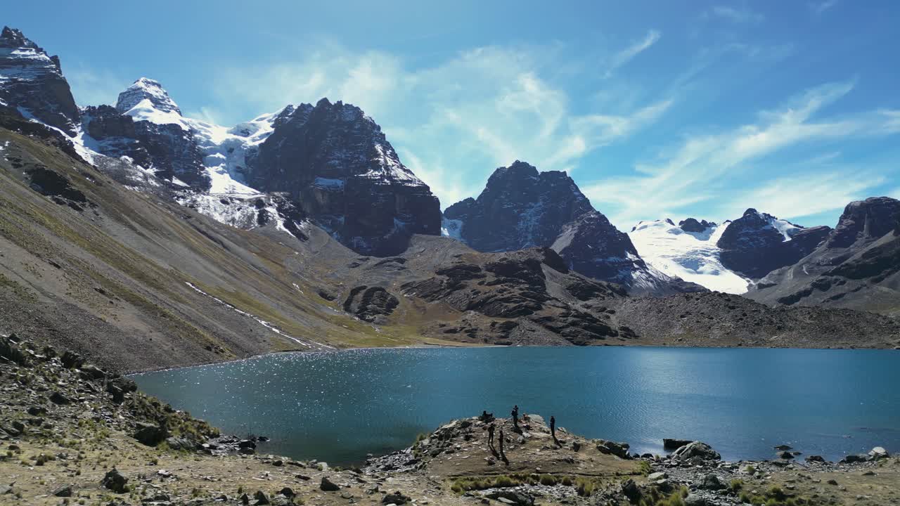 Turisti esplorano un lago alpino soleggiato, la Laguna Zongo, nelle Ande boliviane.