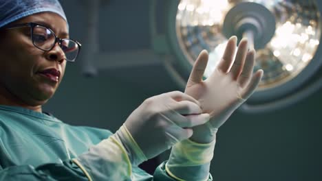 preparing for surgery: a medical professional donning surgical gloves under operation room lights