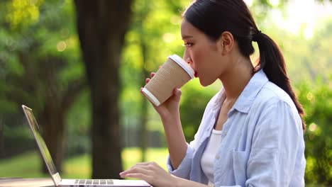 a young woman works on her laptop in a serene outdoor setting, embracing nature while sipping coffee, focused and engaged with her task