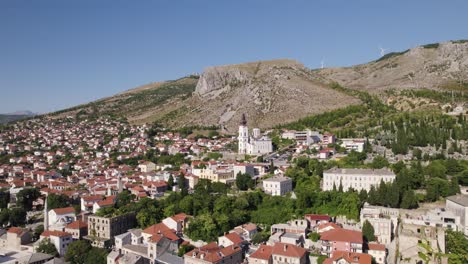 aerial view of mostar cityscape with cathedral of the holy trinity in distance, orbiting shot